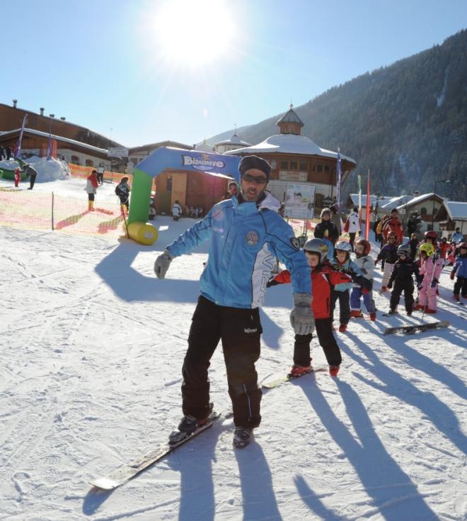 Ski instructor teaching children on snowy slope.